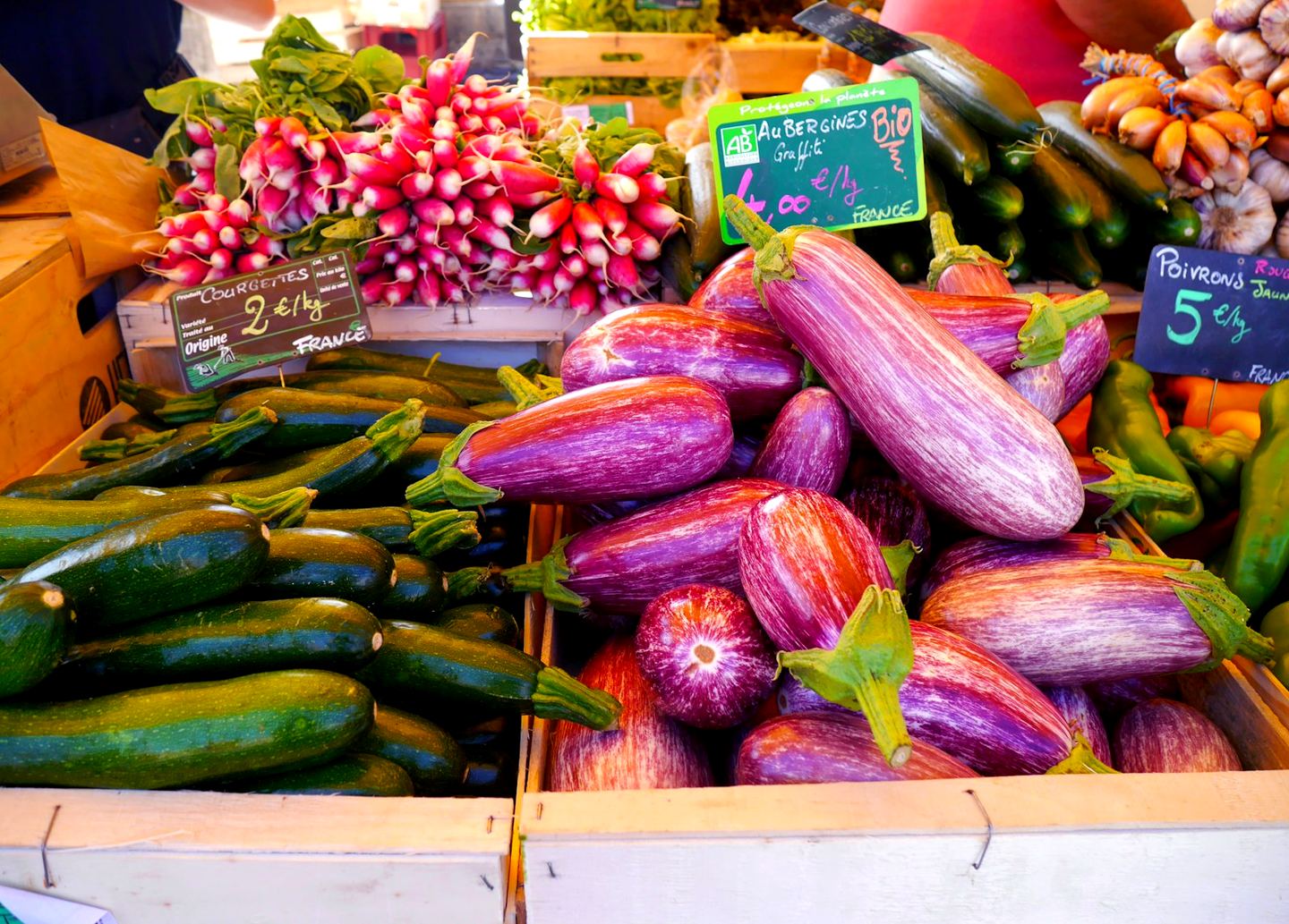 Aubergines zébrées, courgettes et radis sur un étal de marché