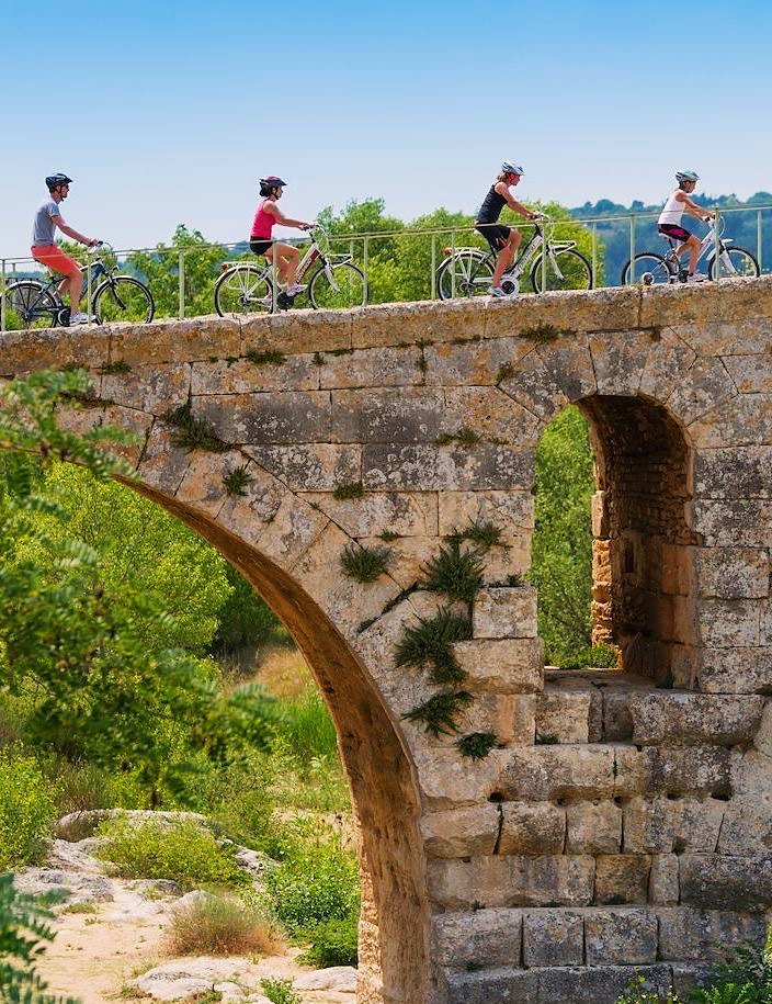 Cyclists crossing the Roman Pont Julien near Bonnieux